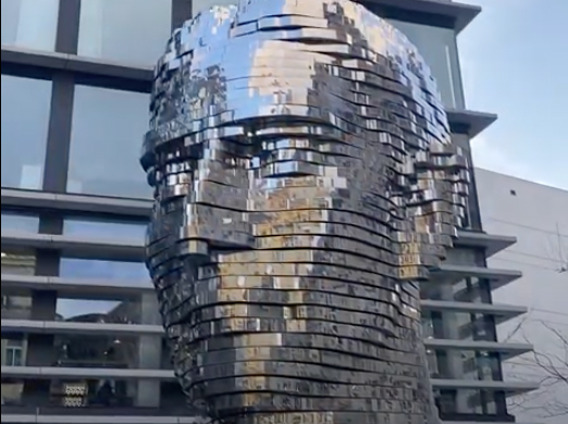 Franz Kafka rotating metallic head on a clear day