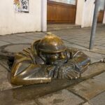 The Čumil statue in Bratislava peeking out from his sewer.