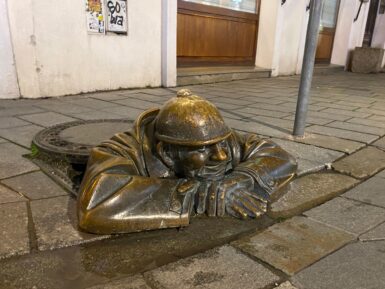 The Čumil statue in Bratislava peeking out from his sewer.