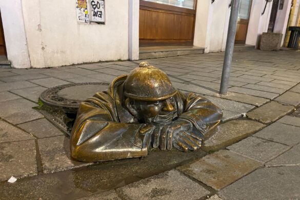 The Čumil statue in Bratislava peeking out from his sewer.