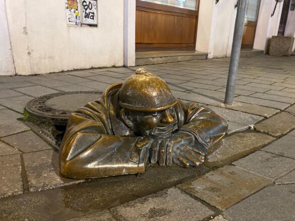 The Čumil statue in Bratislava peeking out from his sewer.