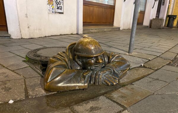 The Čumil statue in Bratislava peeking out from his sewer.